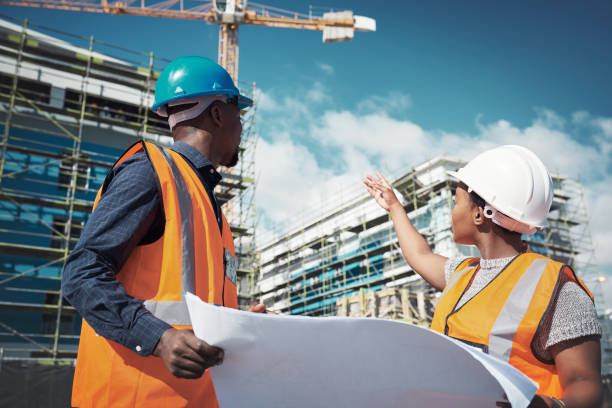 Shot of a young man and woman going over building plans at a construction site